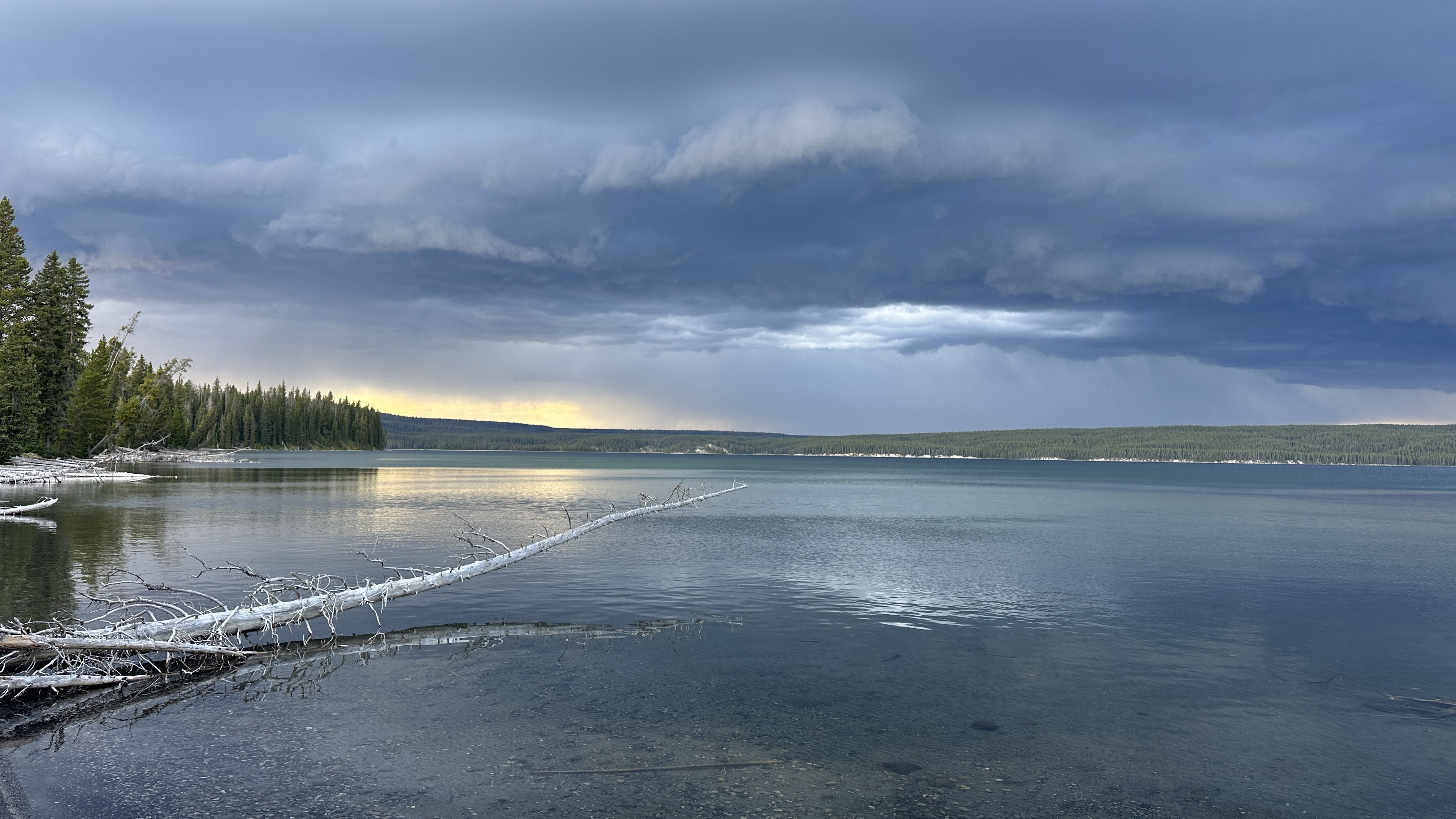 storm over lake with hint of light glowing above the trees